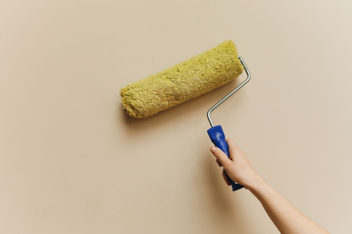 Hand rolling a fresh beige coat over a wall