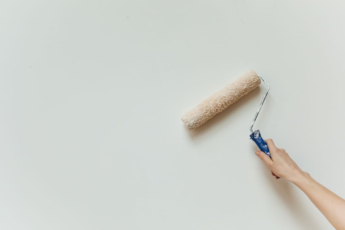 Paint roller applying a fresh neutral coat to a white wall