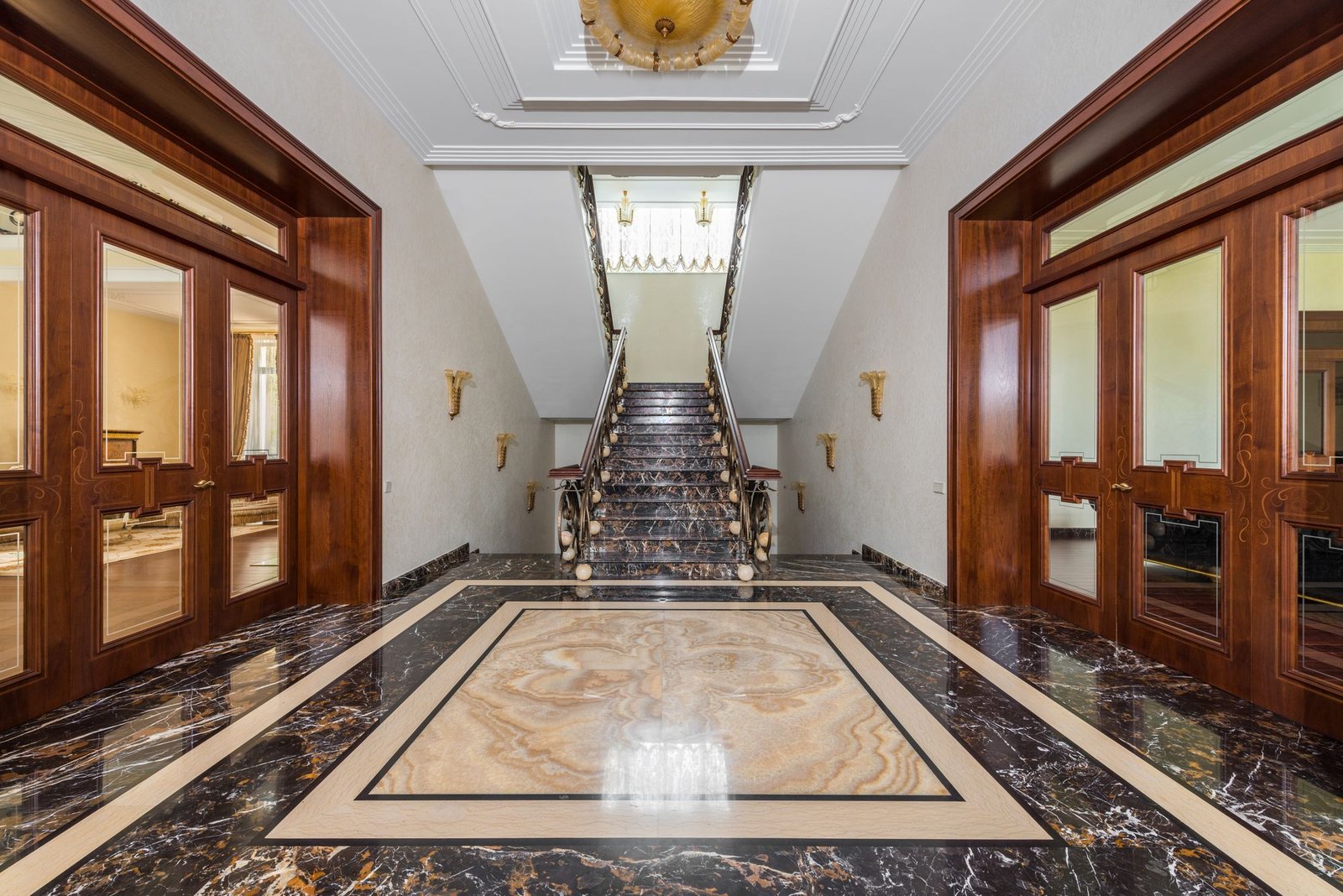 Luxury apartment entrance hall with an ornate inlaid marble floor pattern and staircase
