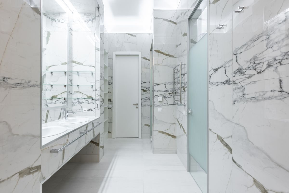 Newly fitted all-marble bathroom with vanity and glass shower enclosure