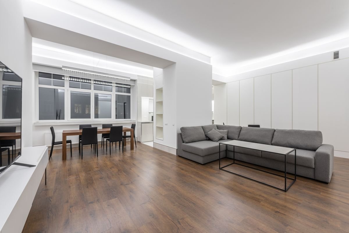 Open sitting area with a cove-lit false ceiling and a grey sectional sofa