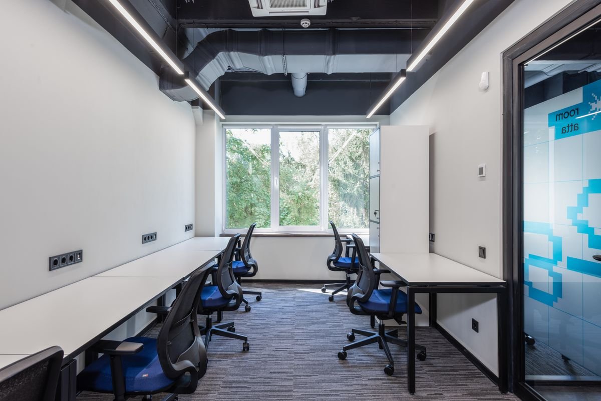 Rows of white workstations beside a large window in a modern office