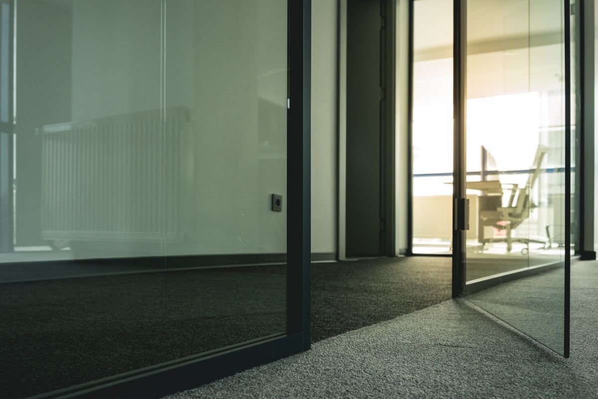 Black metal-framed glass door in a minimalist office partition