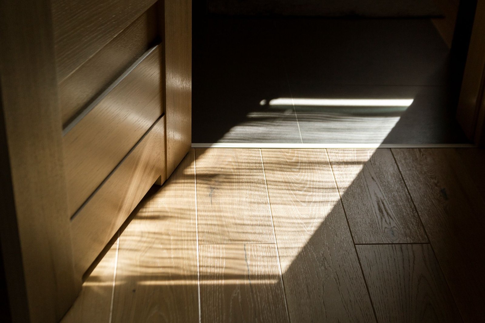 Sunlight casting a rectangular patch on a polished parquet floor
