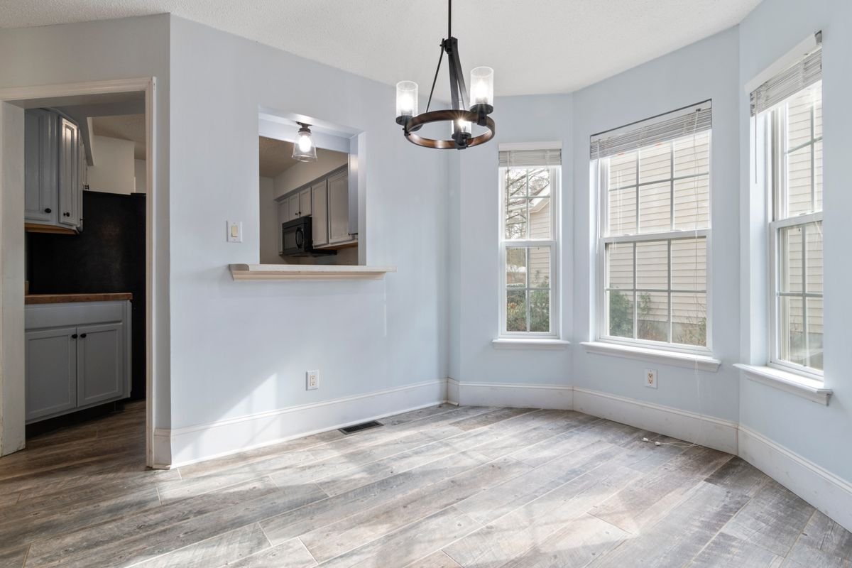 Sunlit empty room with a modern chandelier and wooden parquet floor