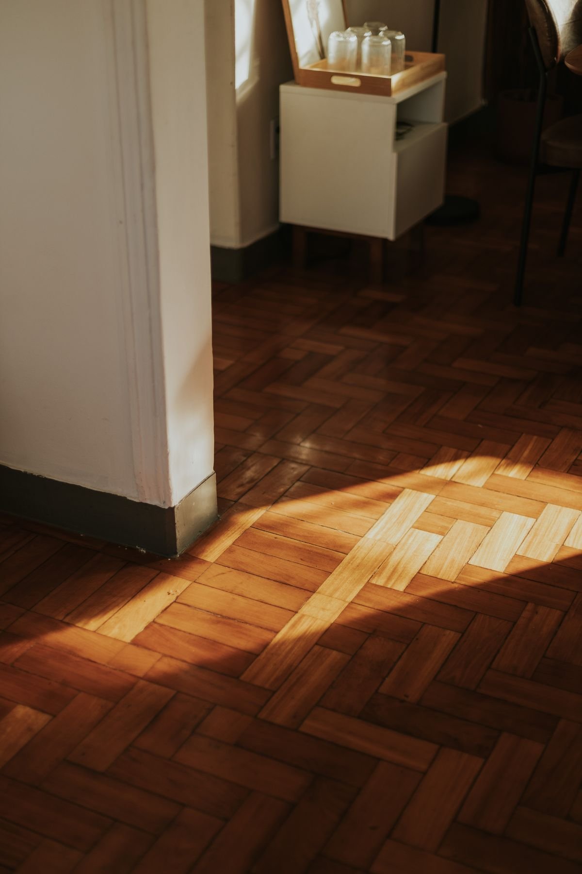 Warm sunlight on wooden parquet flooring in the corner of a room