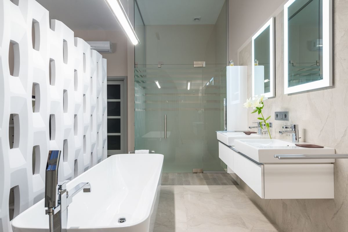 Bathroom with a decorative partition beside the bathtub and a glass shower cabin