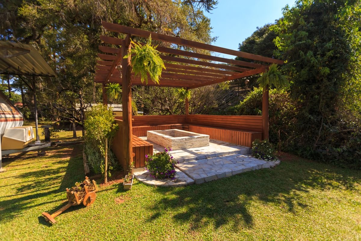 Spacious wooden gazebo in a lush garden setting with stone flooring