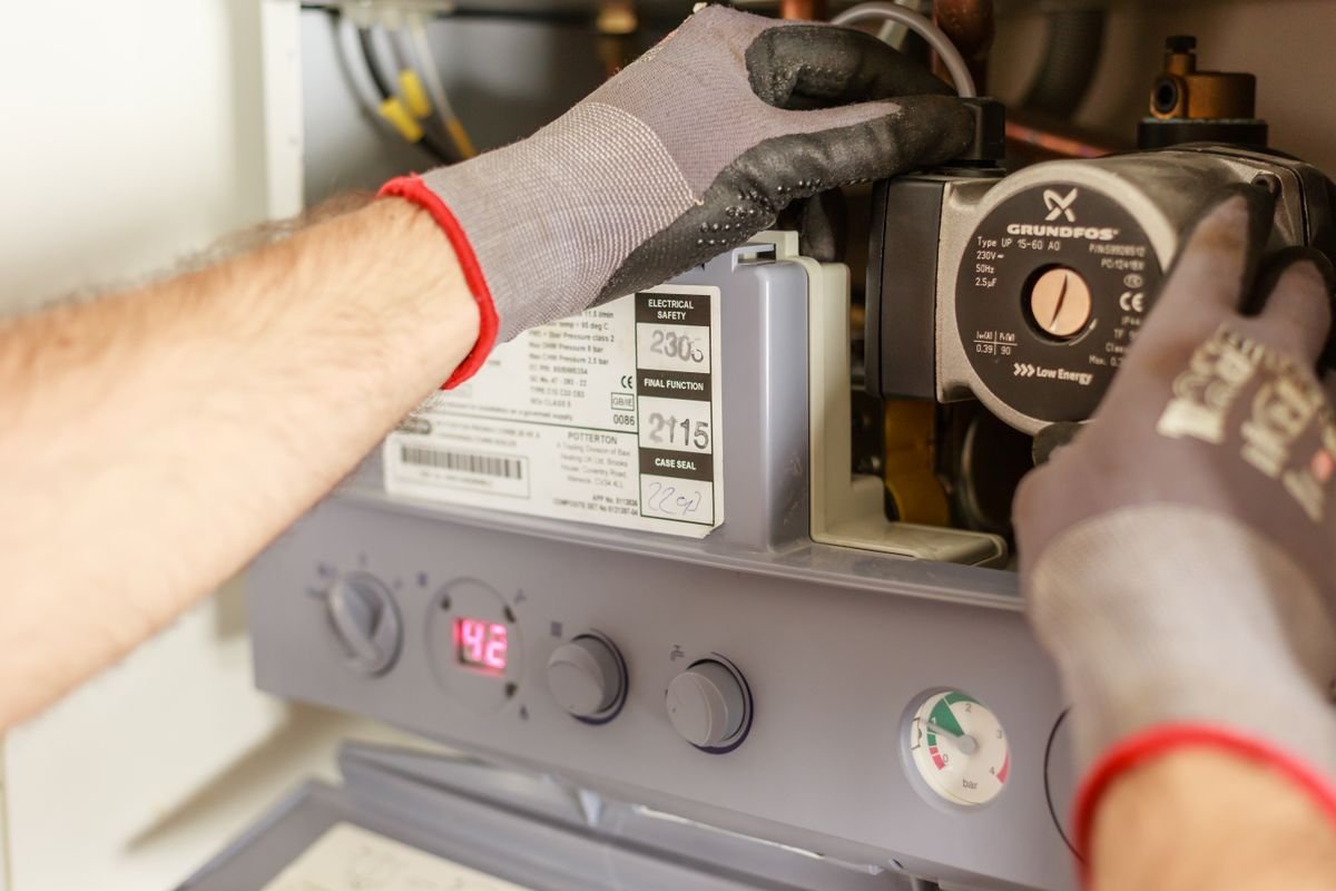 Gloved hands adjusting a boiler circulation pump