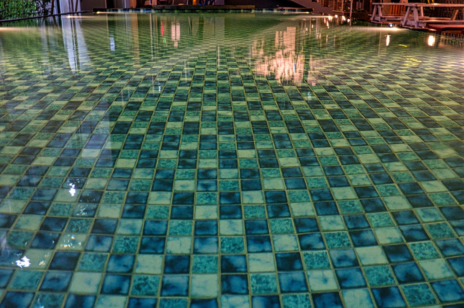Swimming pool with blue tiles under construction, reflecting in clear aqua water