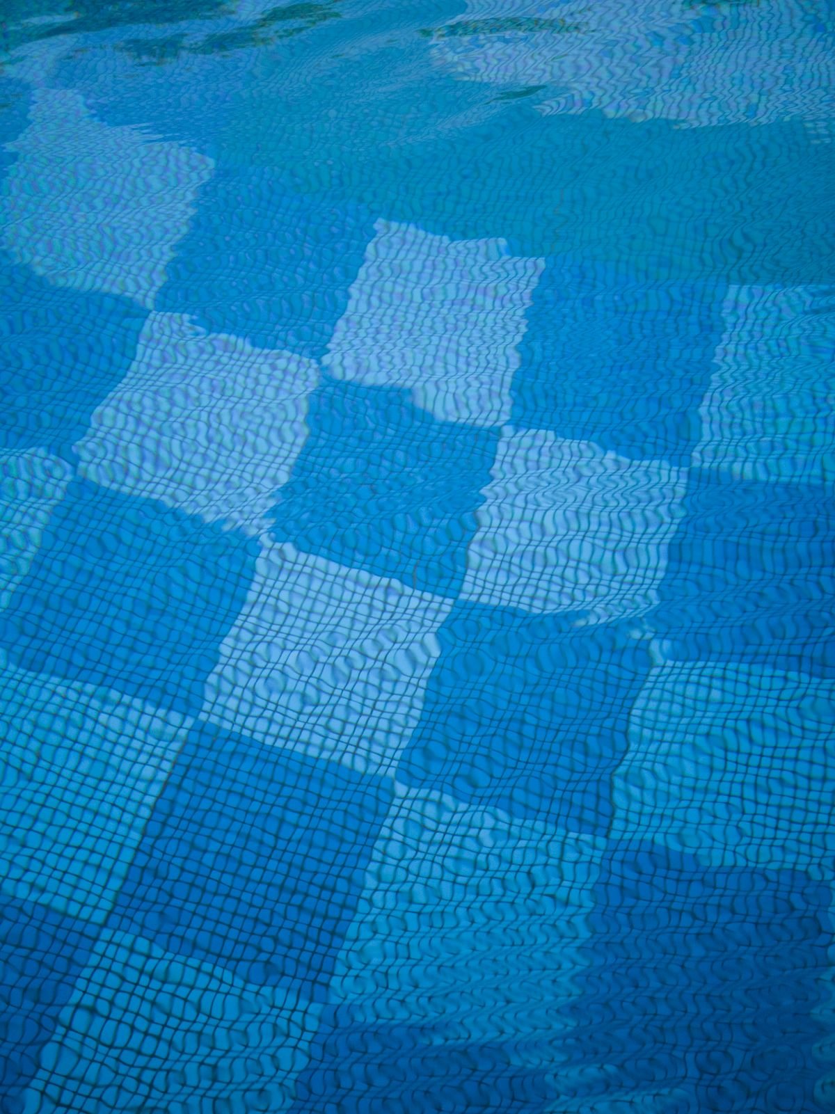 Blue mosaic tiles beneath the water surface reflecting light