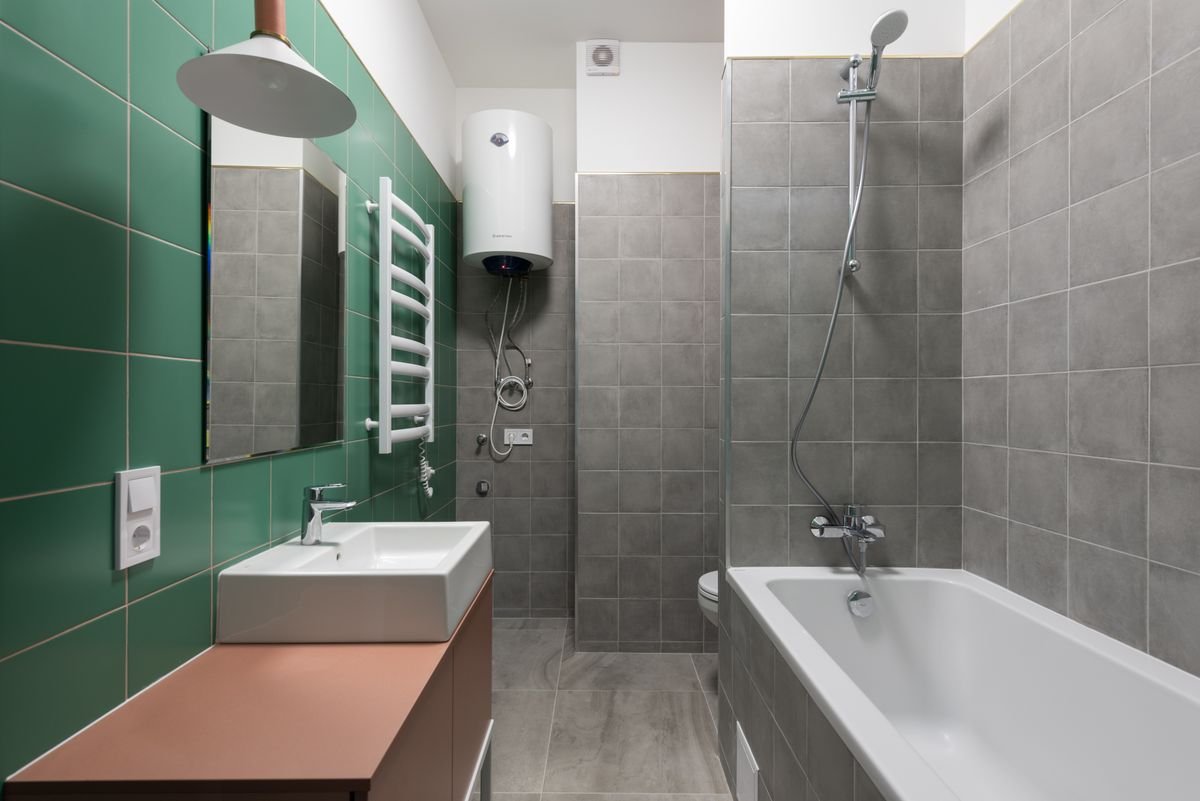 Bathroom with green wall tiles, a terracotta vanity, and a bathtub
