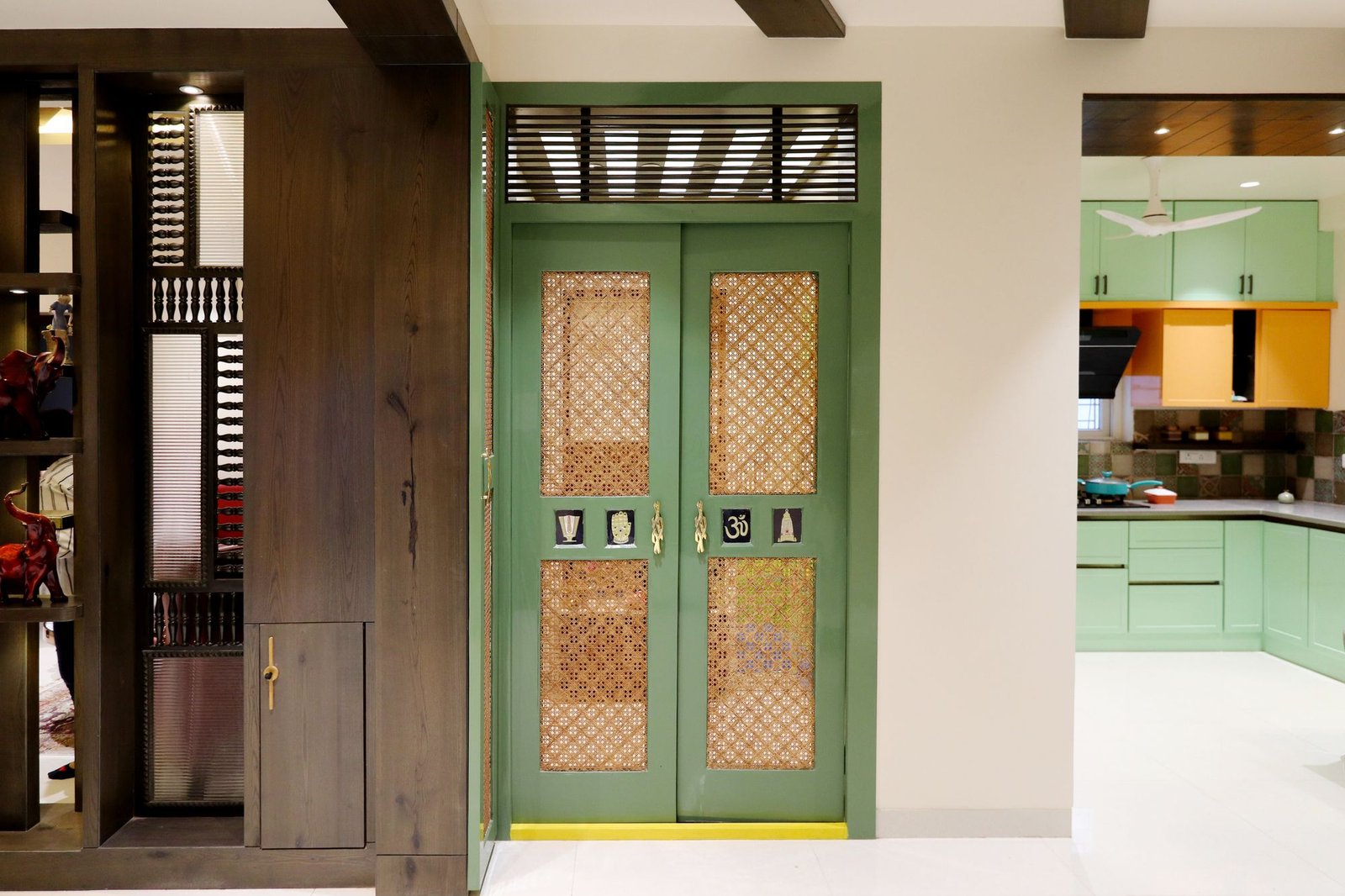Green lattice screen doorway separating a living area from a bright modern kitchen