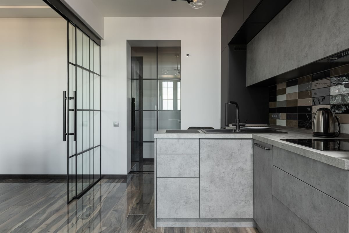 Contemporary kitchen with grey cabinets, a glass partition, and marble details