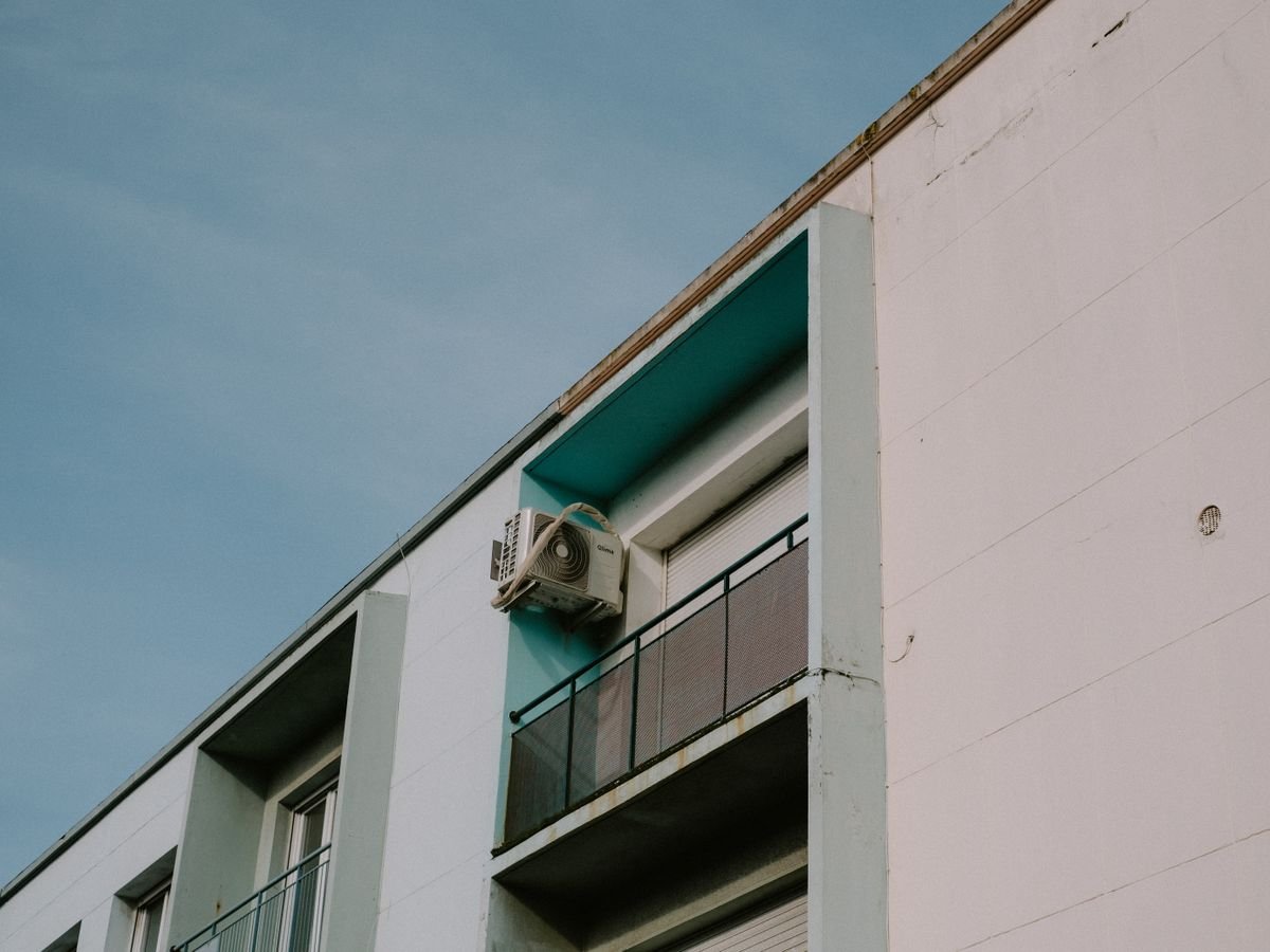 Low angle view of an apartment building balcony with an outdoor AC unit