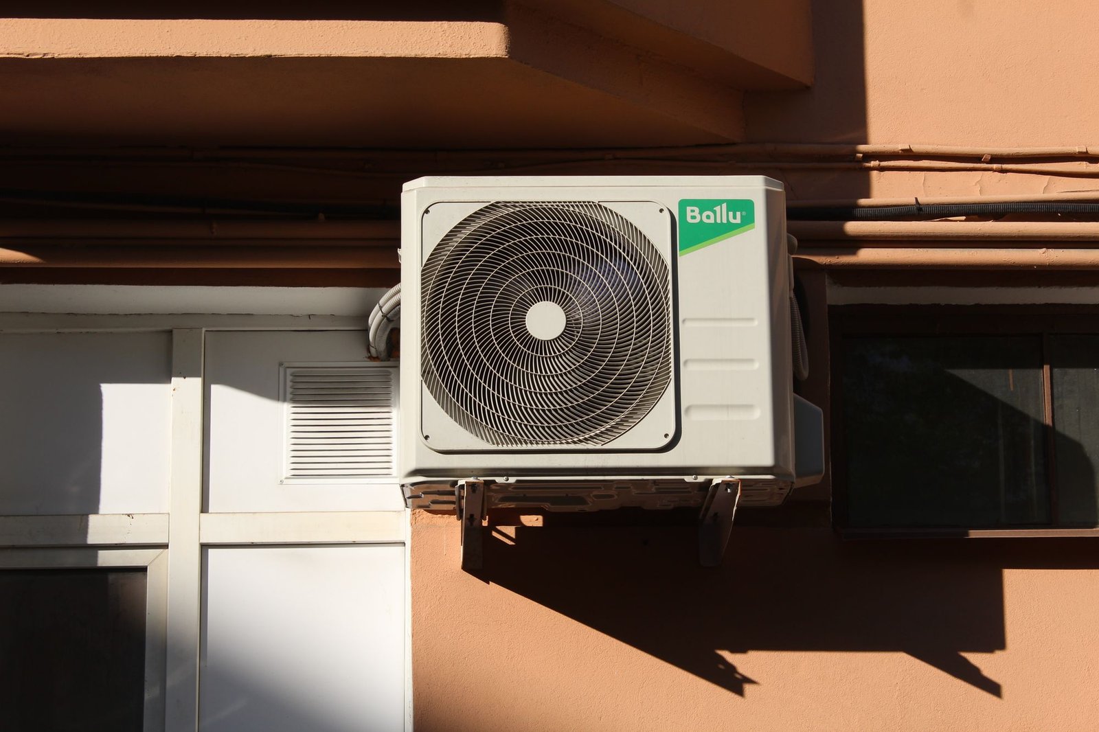 Ballu outdoor split AC condenser unit newly mounted on a building exterior