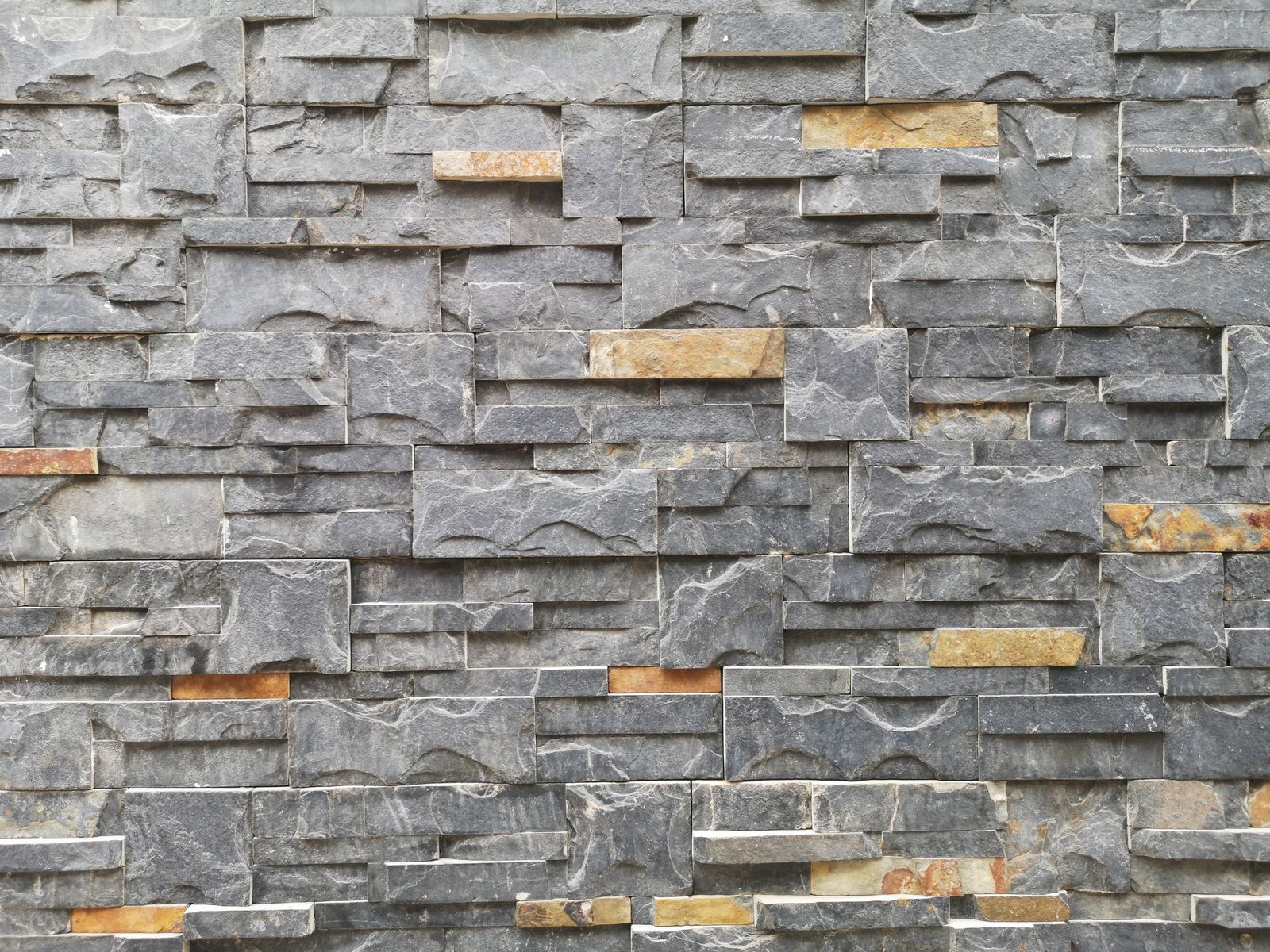Close-up of a textured stone wall made of slate and granite blocks