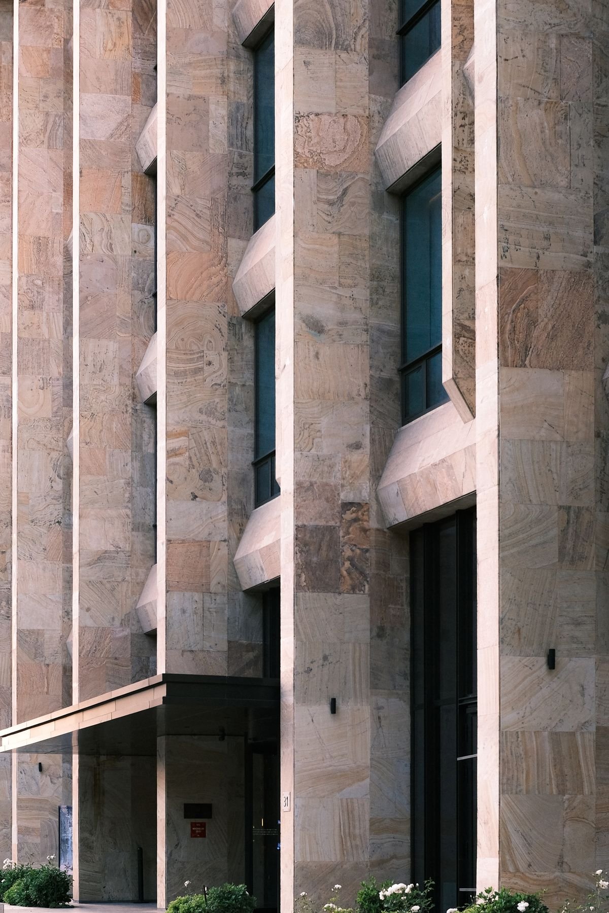 Close view of a modern building exterior with stone textures and vertical patterns