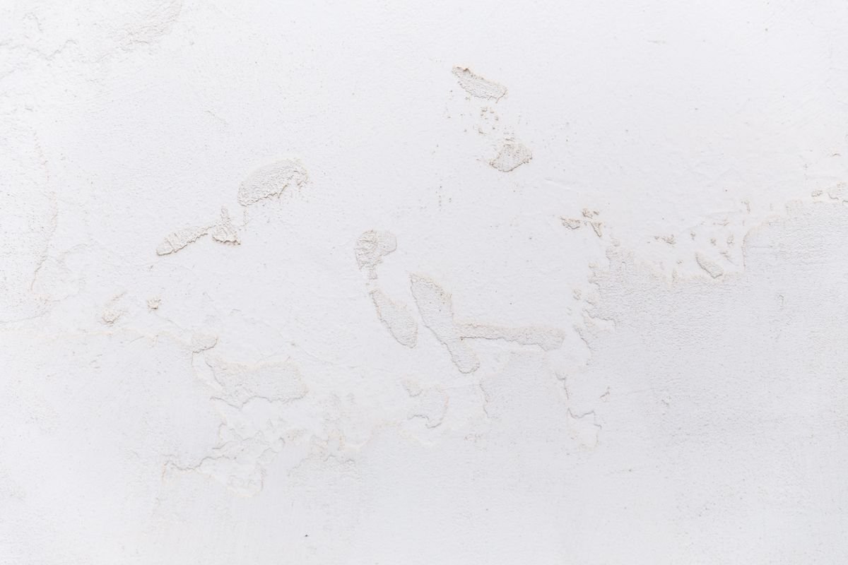 White stucco wall surface showing cracks and chipped areas