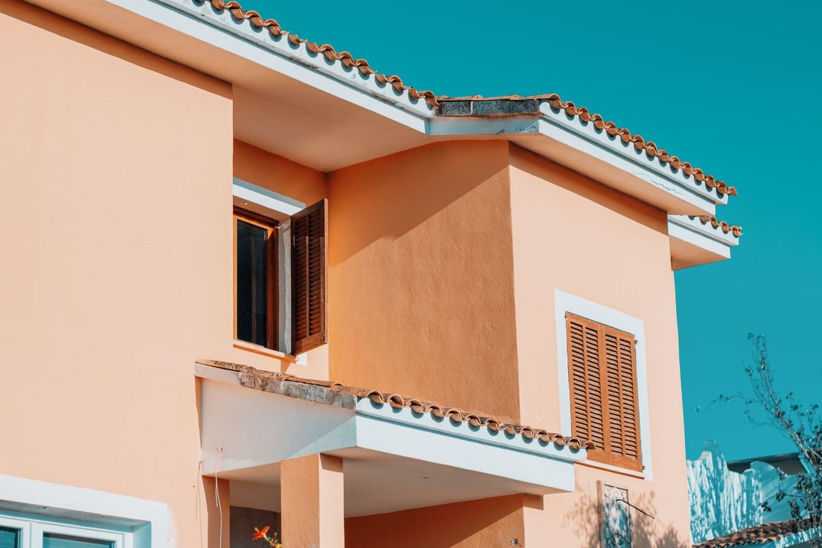 Two-storey house with freshly finished peach stucco walls and tiled roof