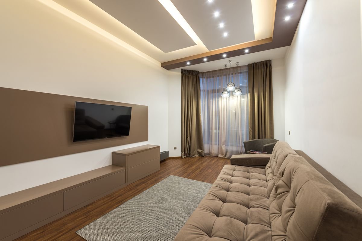 Living room with a suspended gypsum ceiling bordered by a lit cove and spotlights