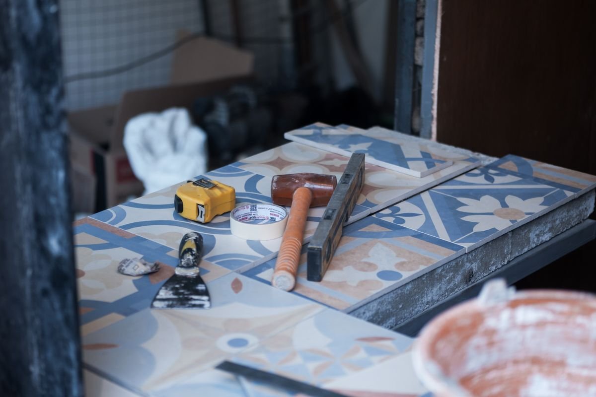 Tiling tools, mortar, and patterned tiles laid out on a job site