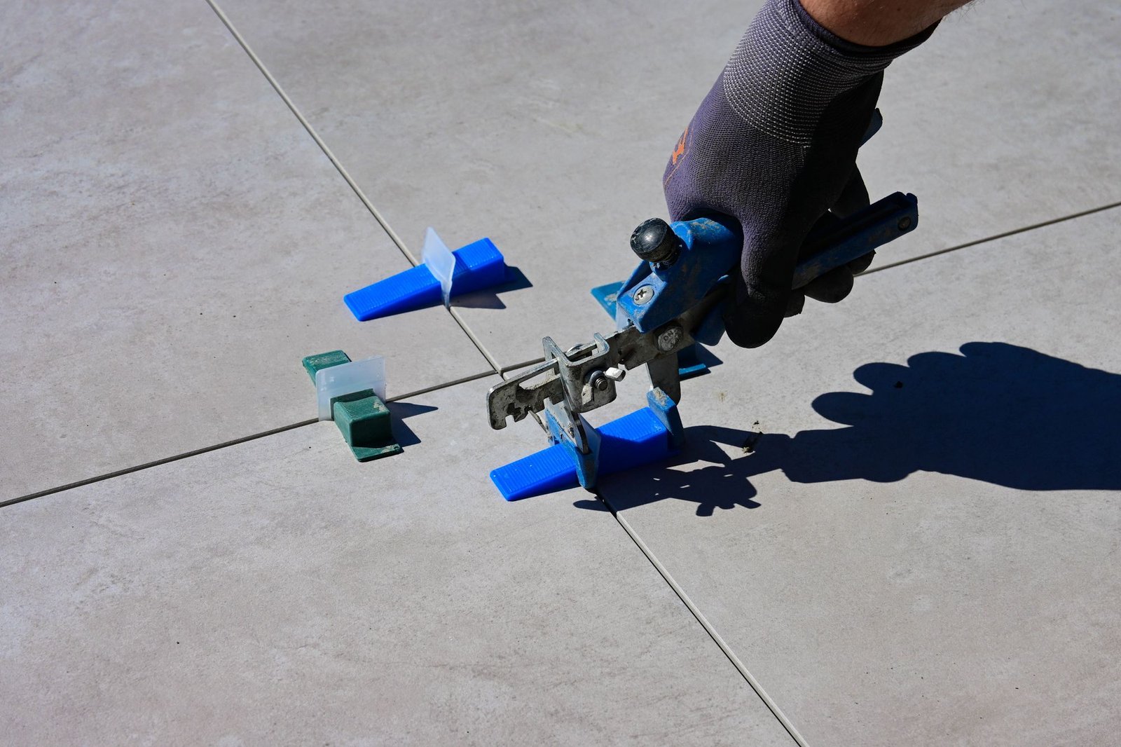 Gloved hand tightening a tile levelling clip on a large-format porcelain tile
