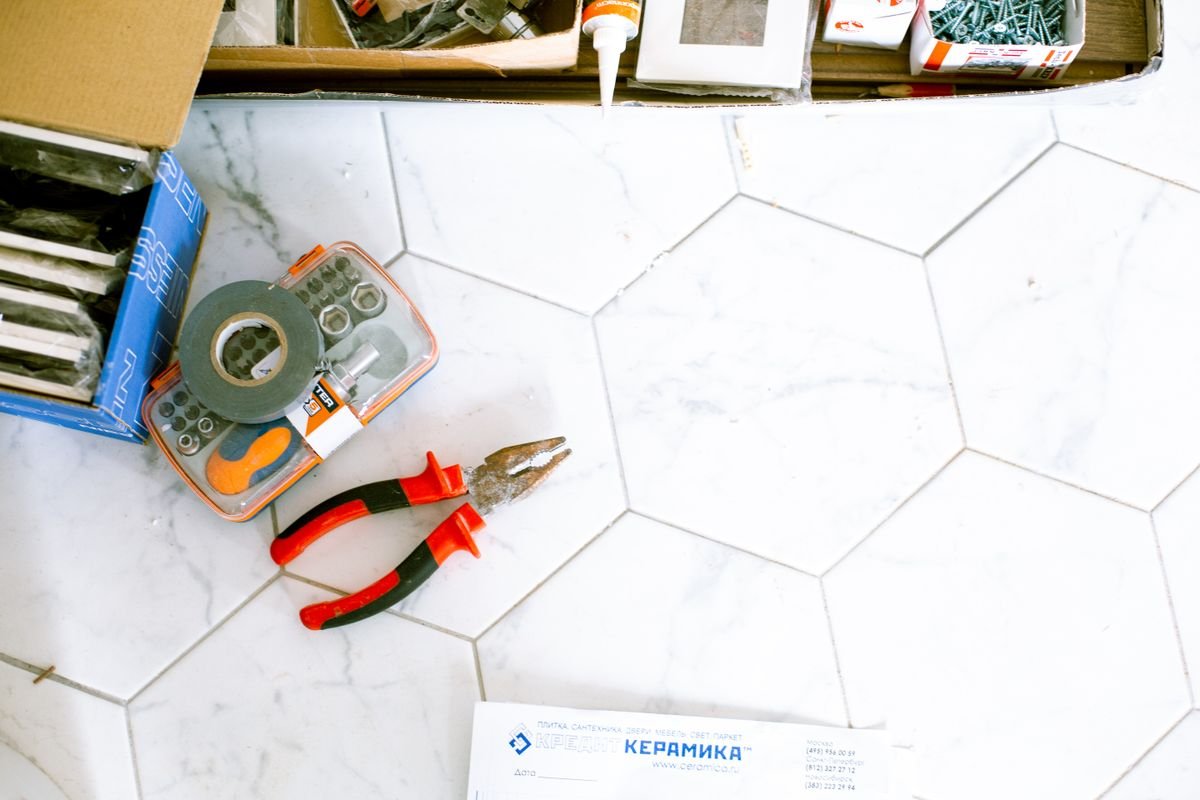 Tools and fixings laid out on a white hexagonal tiled floor