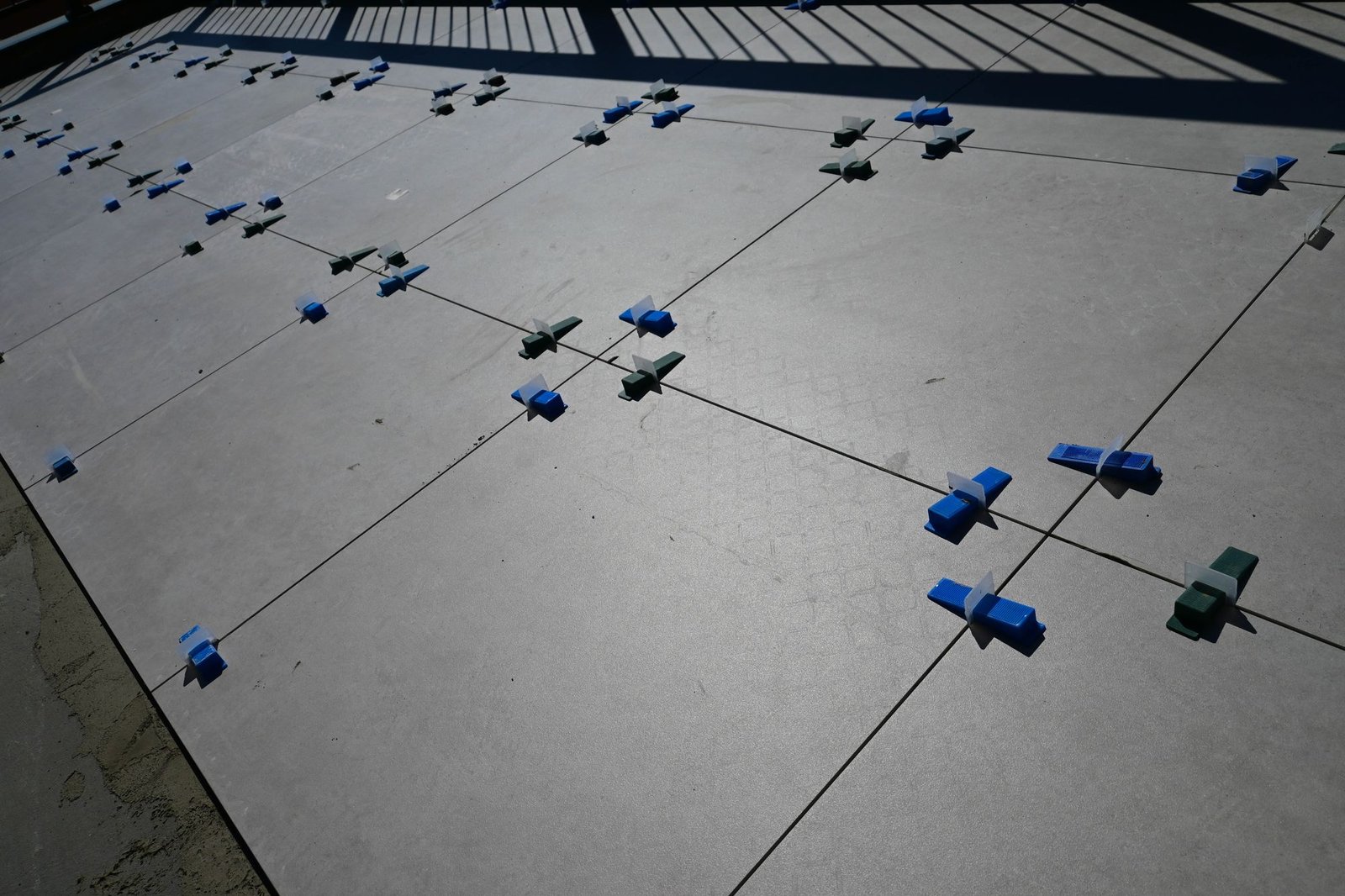 Grid of levelling clips across a large floor of porcelain tiles