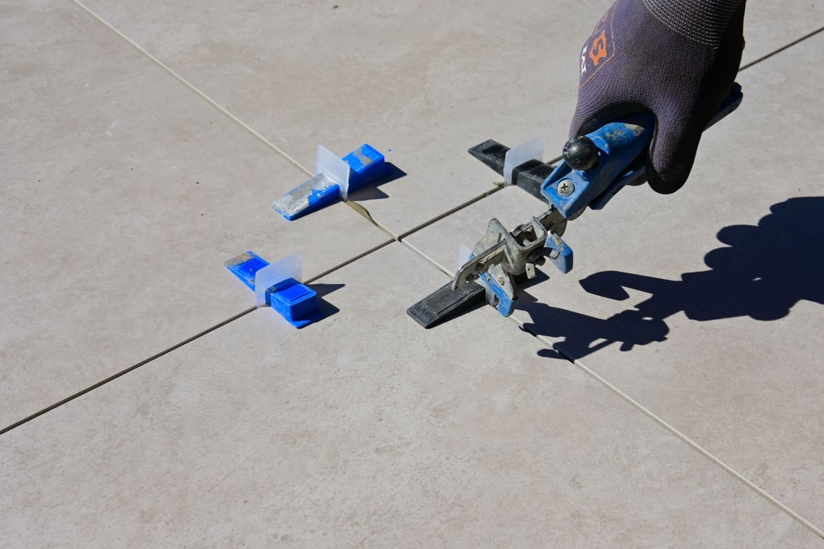 Levelling pliers tightening blue clips on a large-format tile