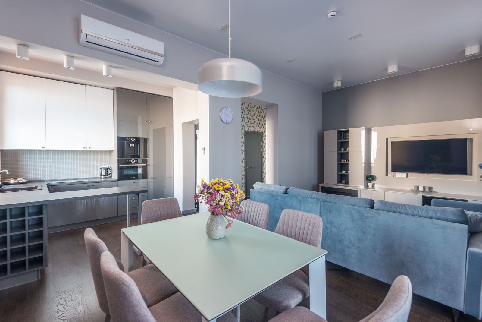 Finished open-plan living, dining, and kitchen area with a blue sofa and pendant lighting