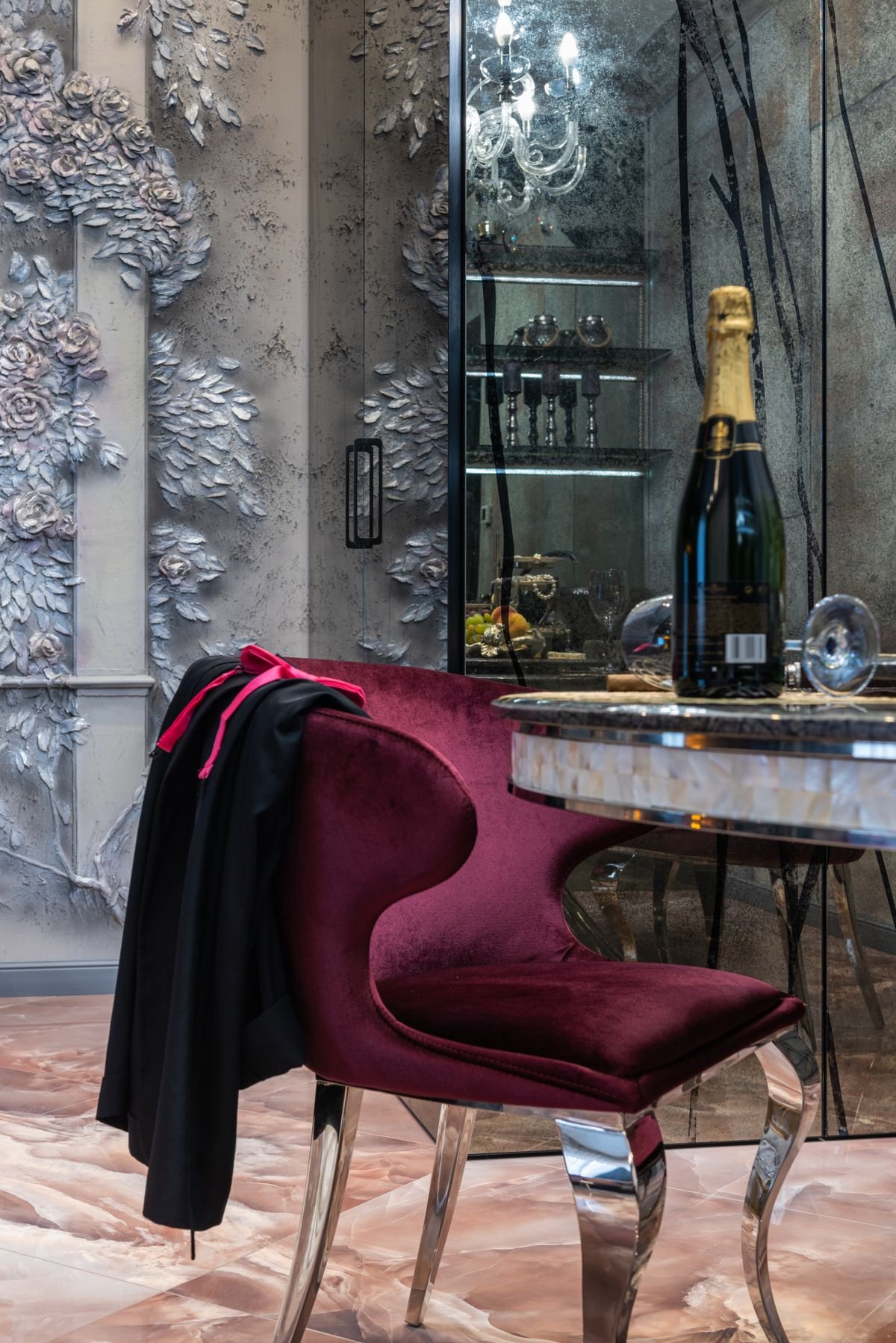 Living room with a sculptural magenta armchair beside a marble feature wall