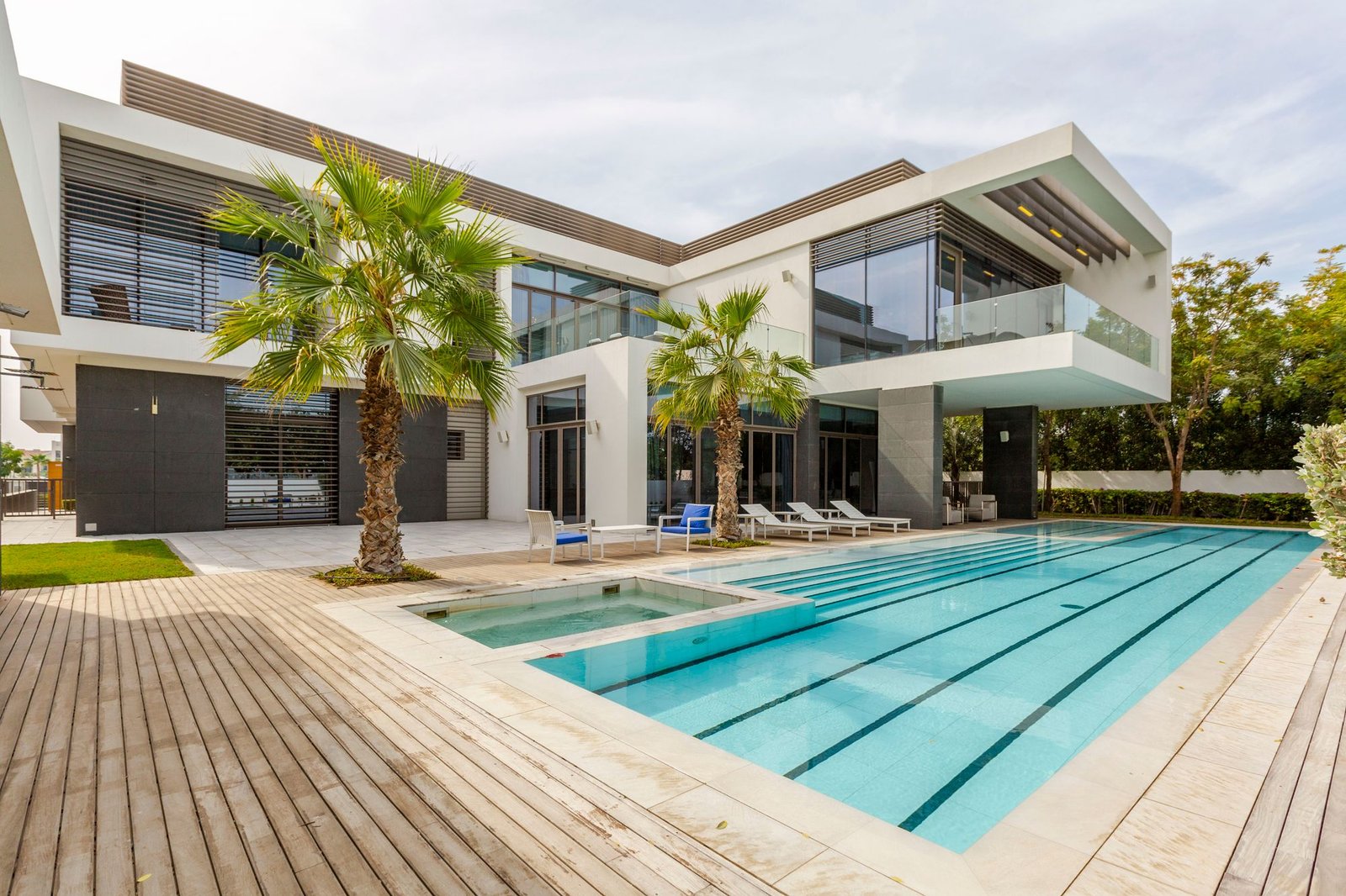 Modern Dubai villa with smooth painted white and grey facade, pool, and palm trees