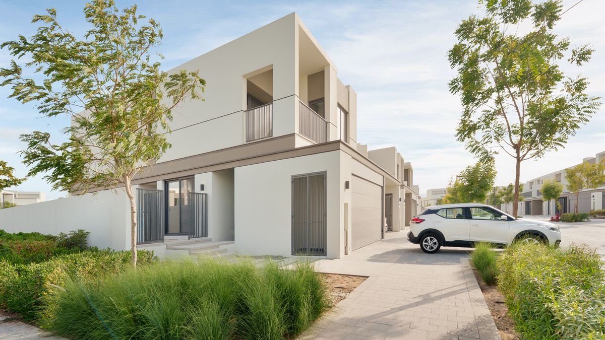 Modern two-storey villa with cream painted exterior and a parked car in the driveway