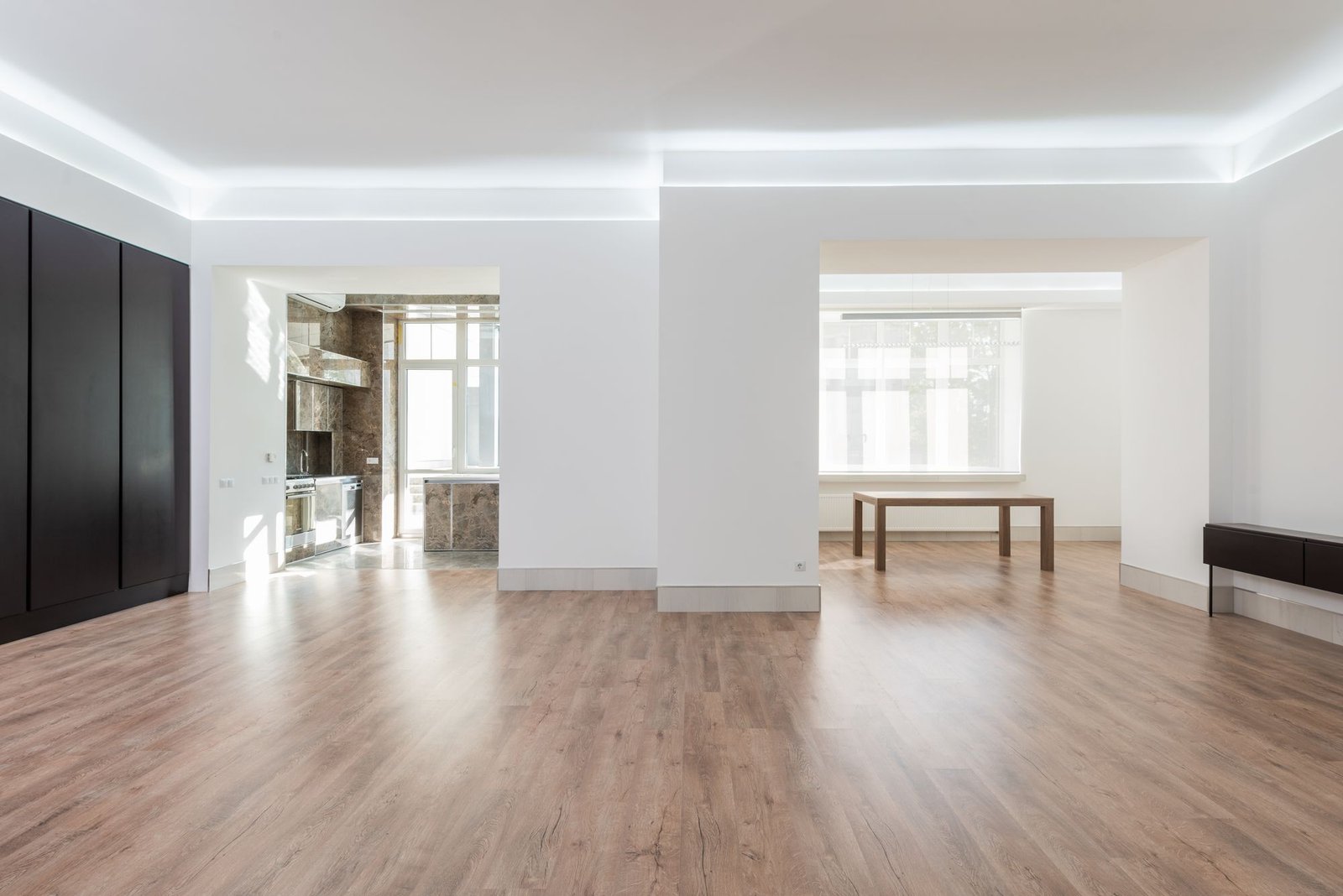 Bright open-plan room with light grey wood-look vinyl plank flooring and cove lighting