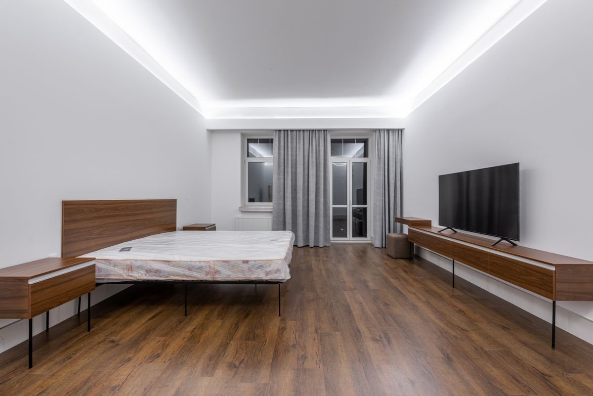 Bedroom with a dark wood-look floor, ceiling cove lighting, and a media unit