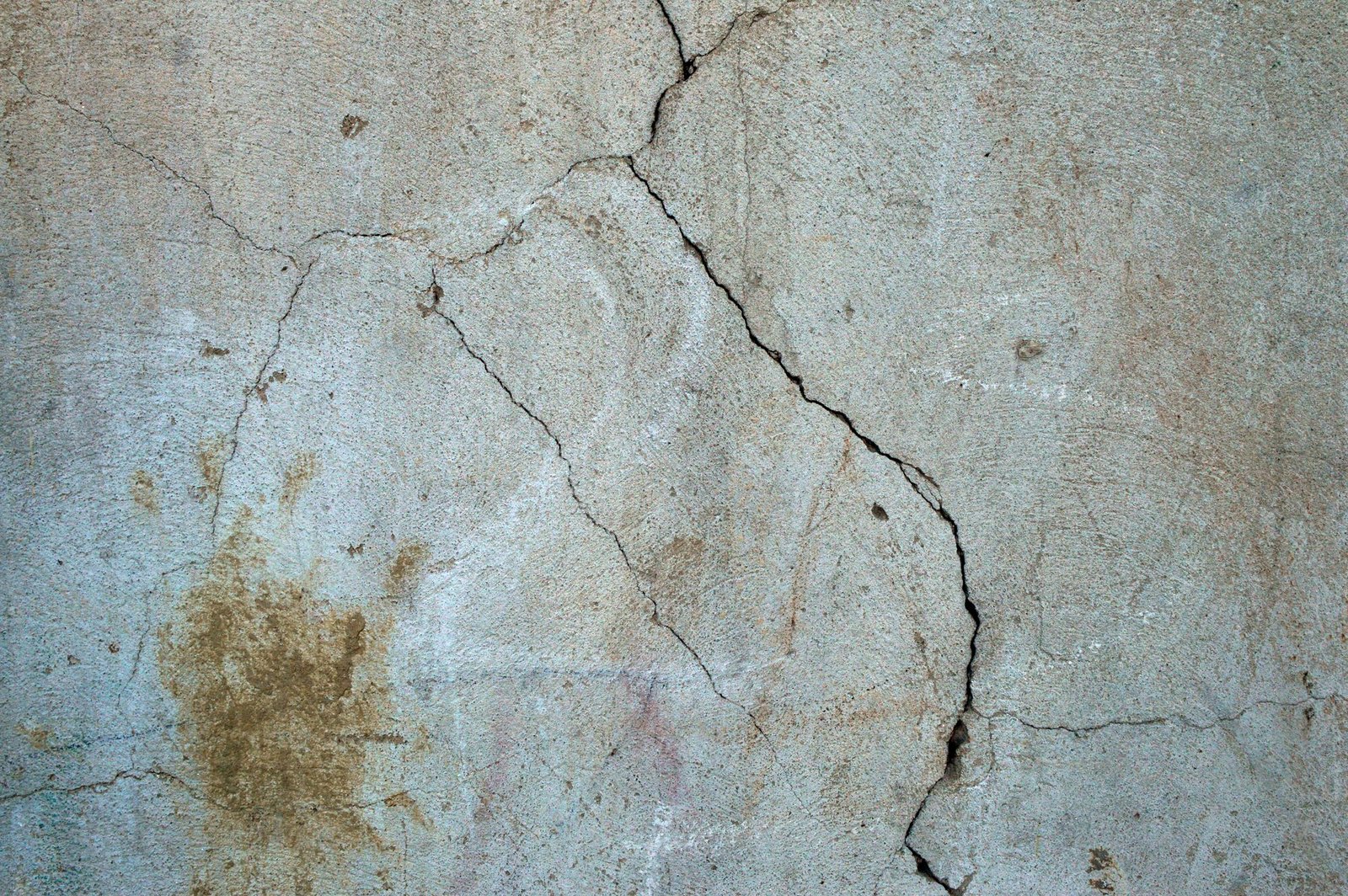 Crack running down a stained grey-green wall surface