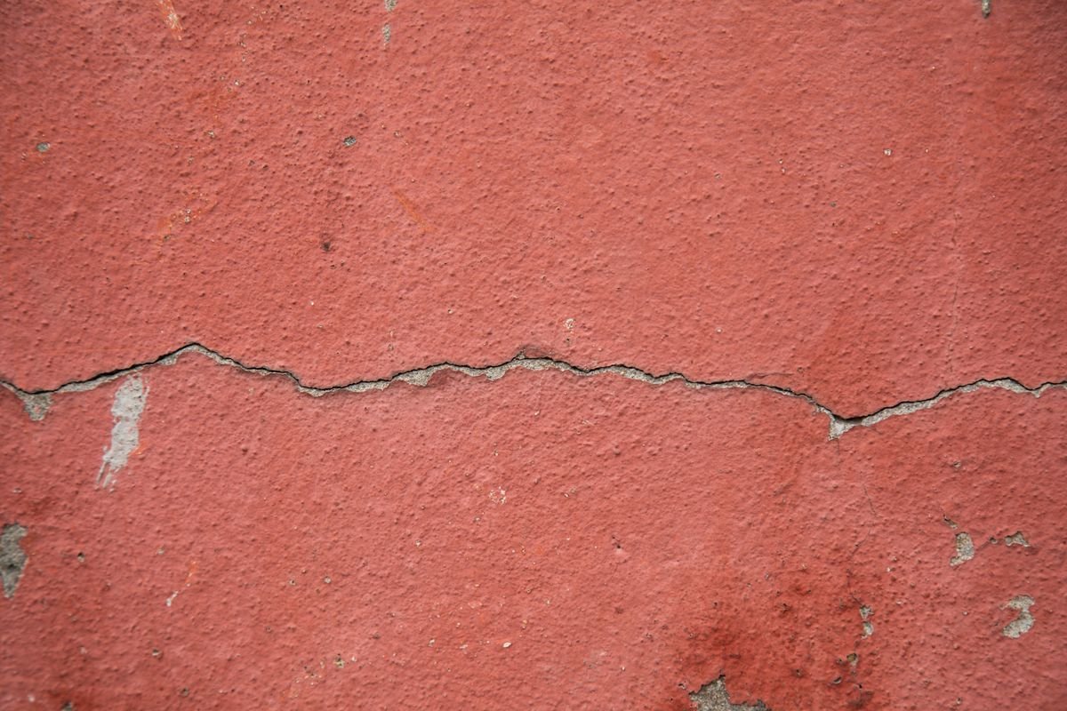 Crack running through a red painted wall surface