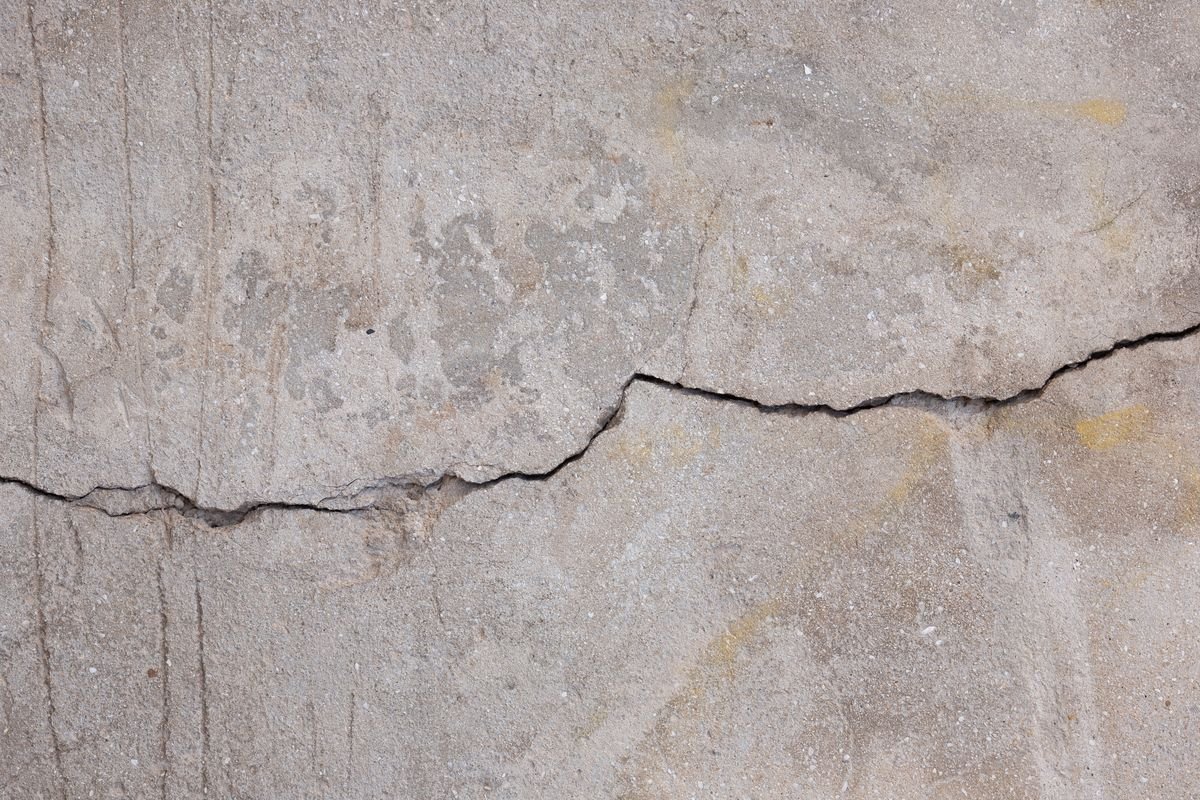 Crack across a sun-weathered light-coloured wall surface