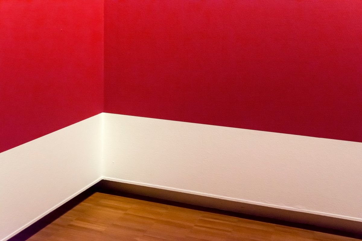 Red accent wall with white wainscoting in a minimalist room