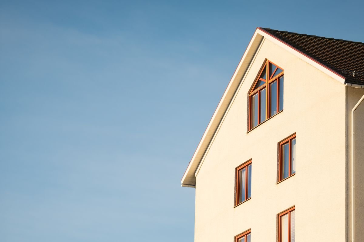 Painted beige exterior facade of a house against a clear blue sky