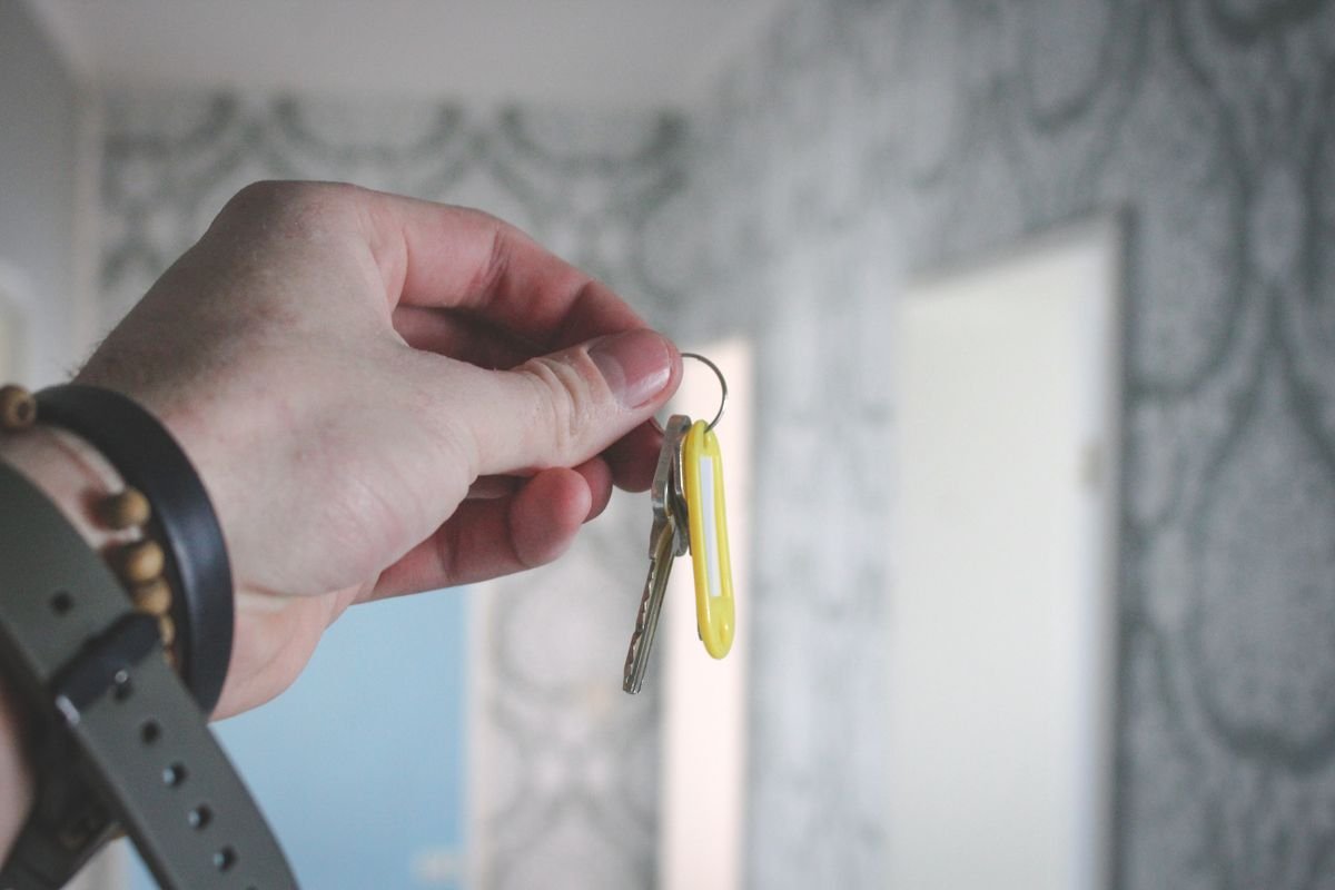 Hand holding house keys in a freshly decorated hallway