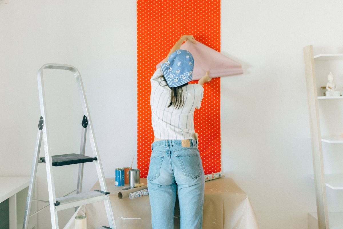 Woman applying polka dot wallpaper during a home makeover