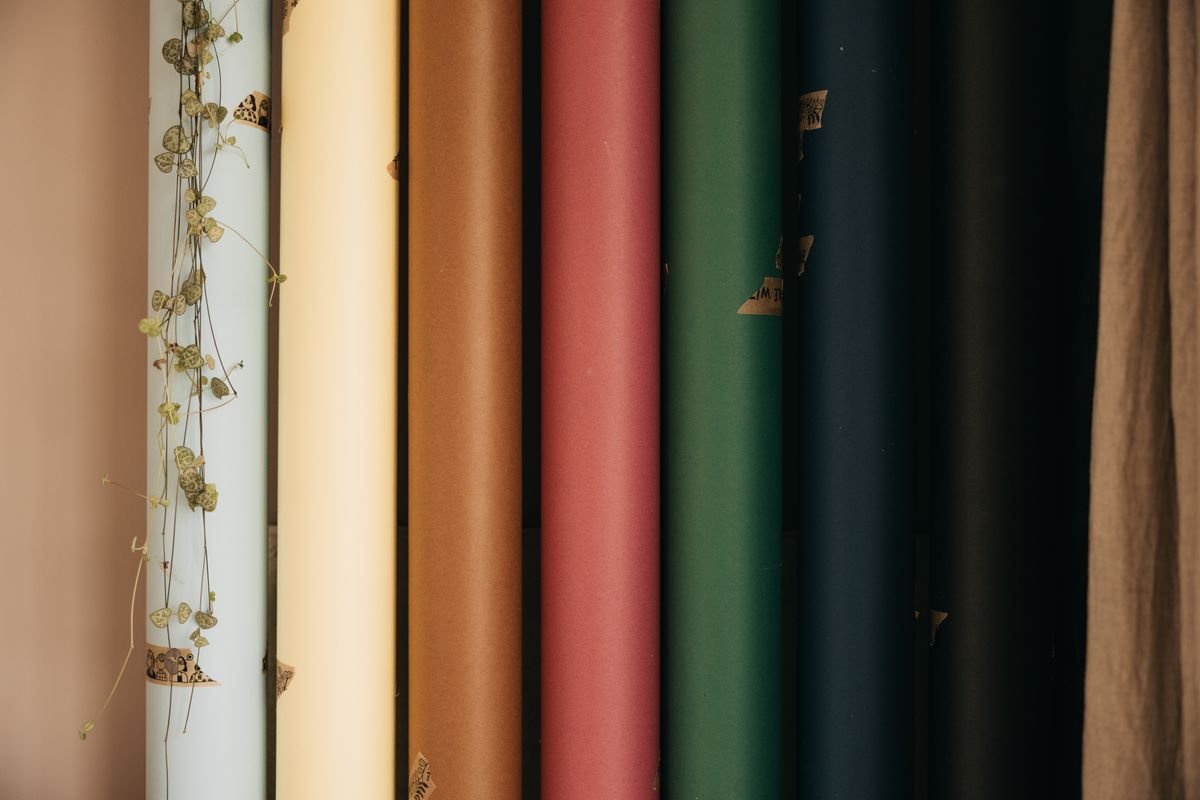 Rolls of paper in assorted colours standing upright side by side