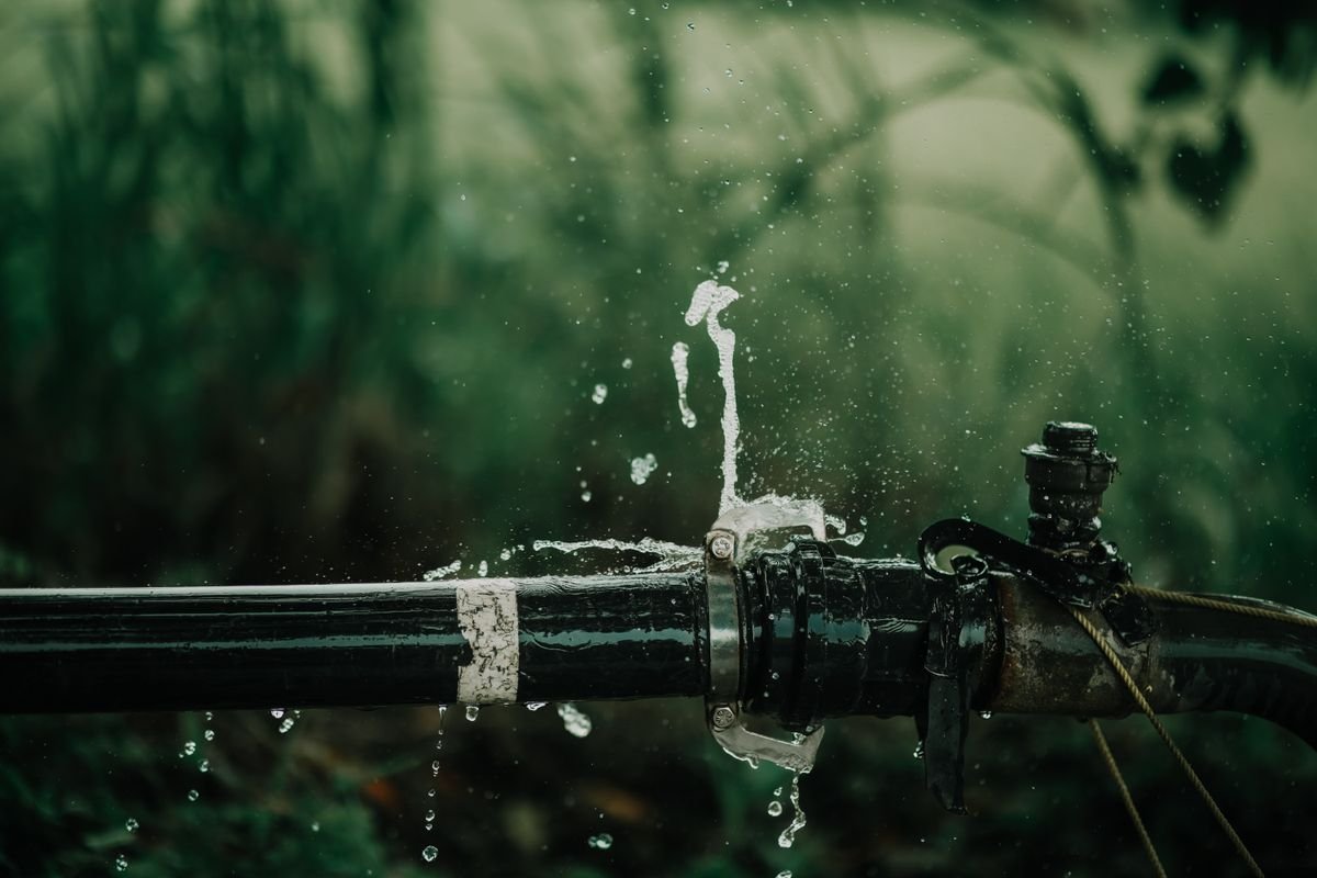Water spraying from a leaking pipe joint outdoors
