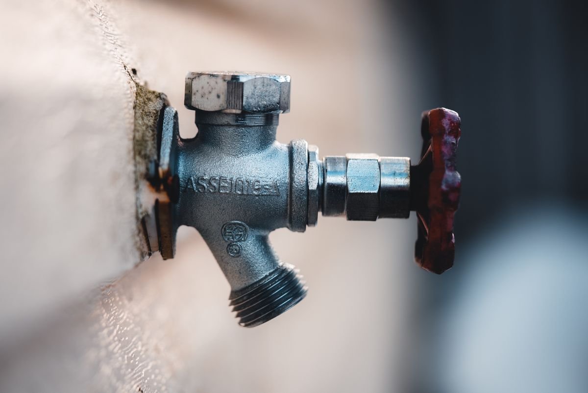 Close-up of a metal shut-off valve mounted on an exterior wall