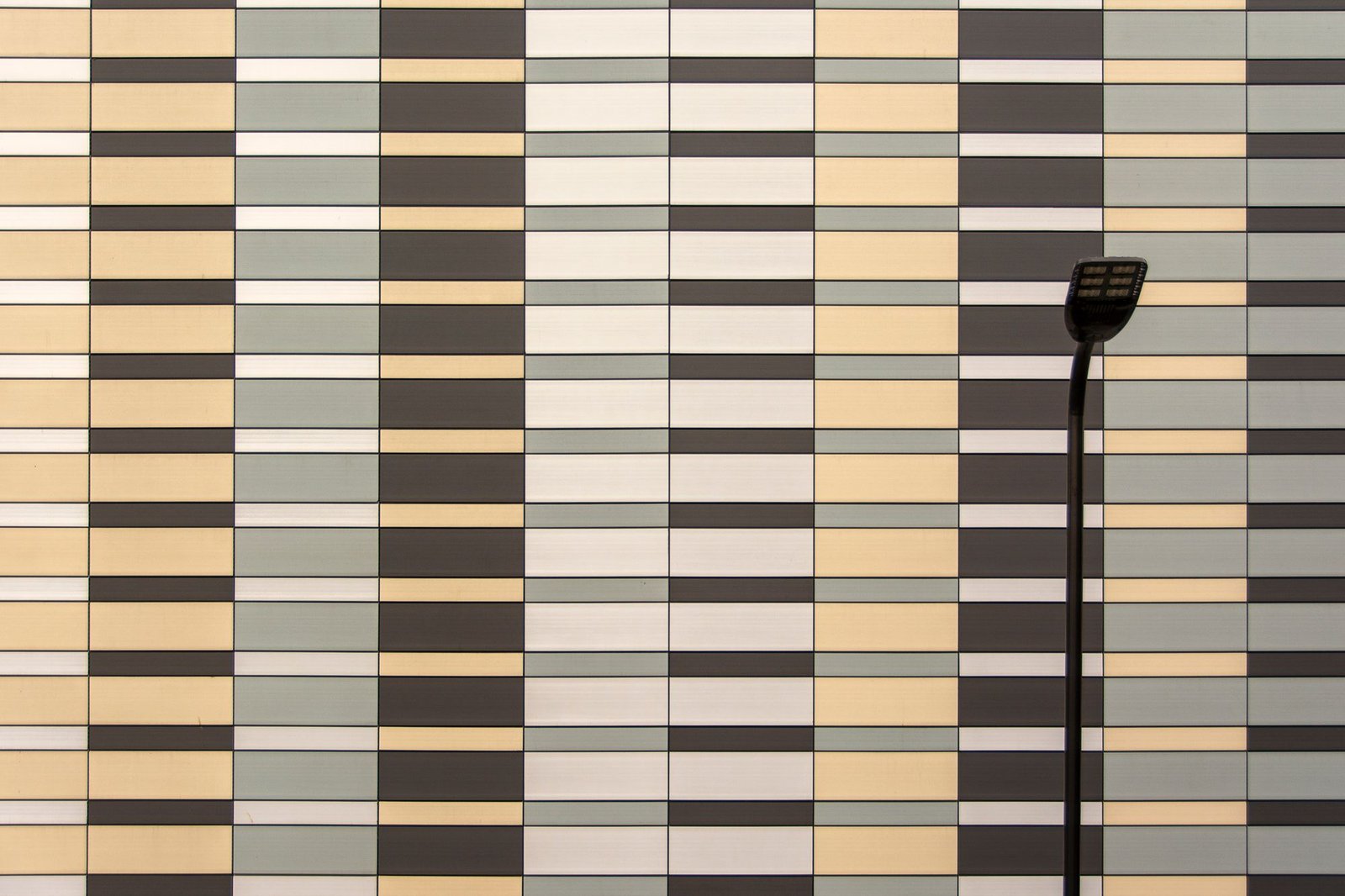 3D geometric patterned wall of staggered tiles in yellow, grey, and black
