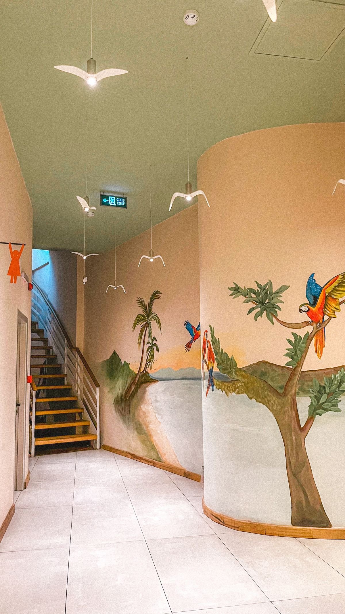Scenic mural on a hallway wall with painted palm trees and parrots