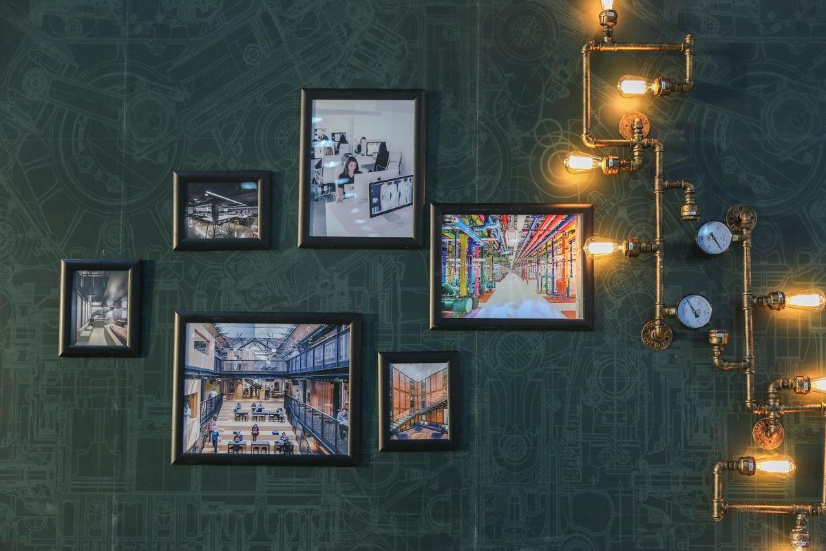 Dark green textured wall with framed pictures and vintage pipe lamps