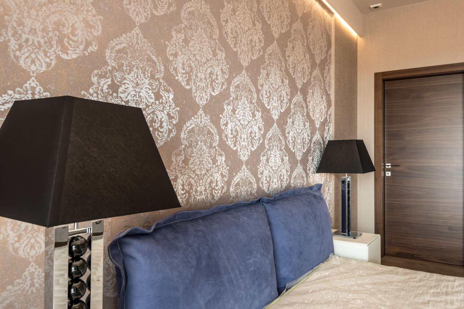Bedroom wall finished in an elegant taupe damask wallpaper with matching trim